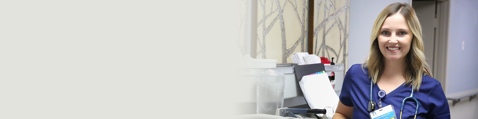 A nurse standing in the hallway next to a nurse's cart