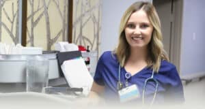 A nurse standing in the hallway next to a nurse's cart